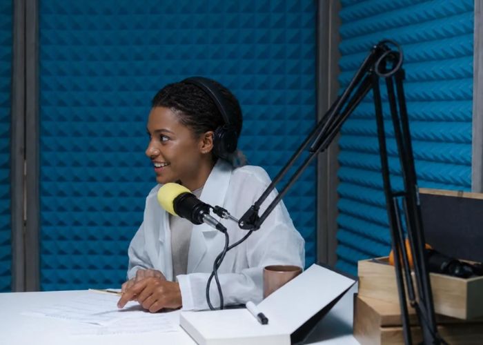 Woman in headphones recording voice-over content beside a microphone in a soundproofed studio