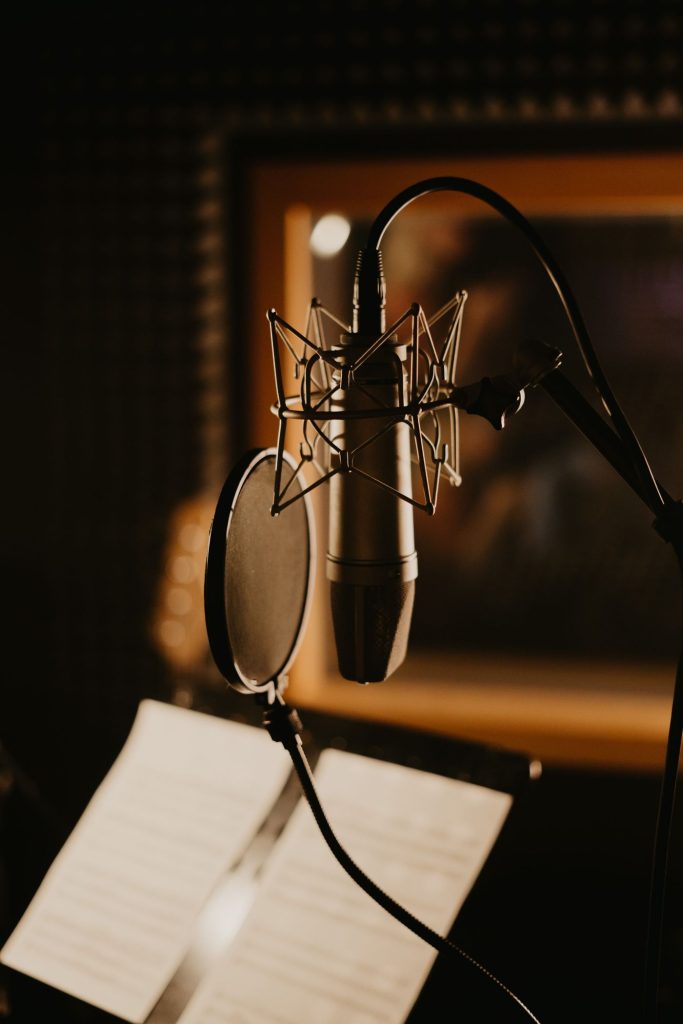 Studio microphone with pop filter in a dimly lit sound recording studio