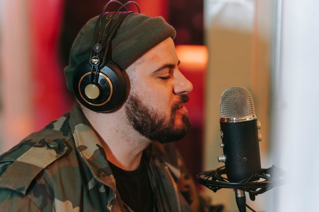 Vocalist in headphones singing into a microphone during a music recording session