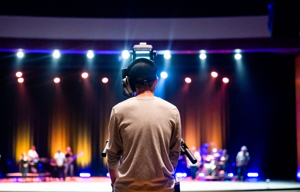 Camera operator filming a live event production from behind the stage