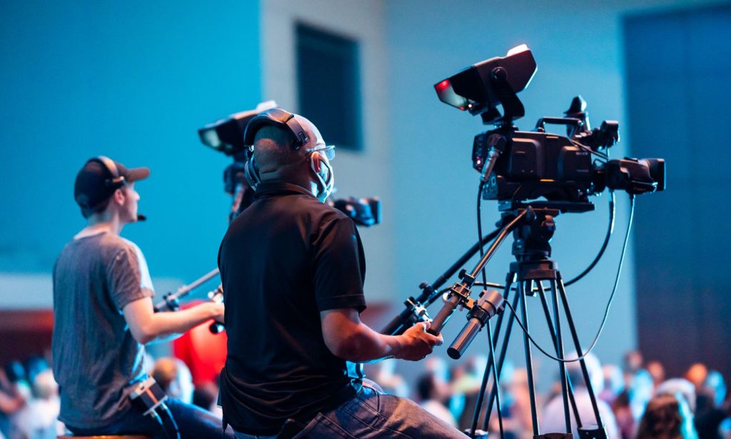 Two camera operators covering a live event with professional video cameras