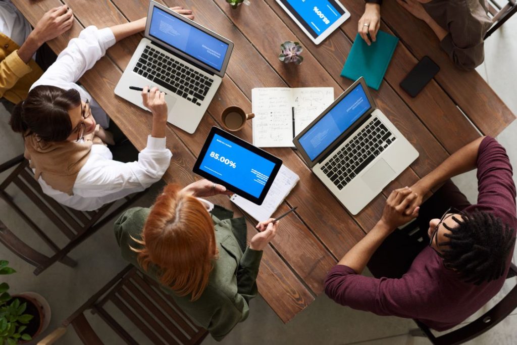Diverse team discussing business growth strategy with laptops and tablets at a table